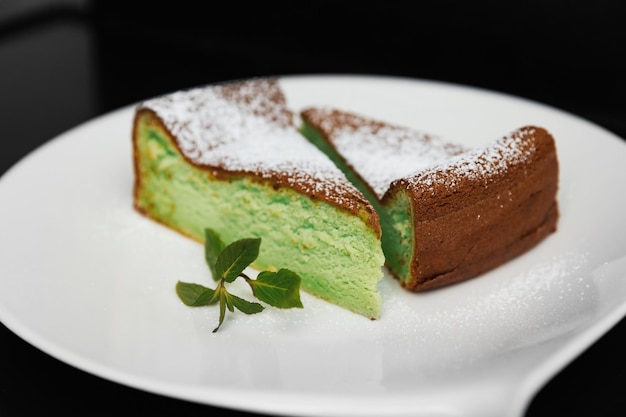 Cheesecake verde accanto a decorato con menta su sfondo nero