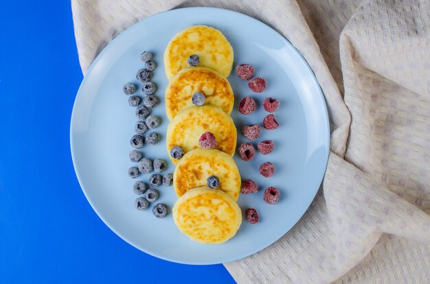 Cheesecakes in un piatto blu con frutta congelata