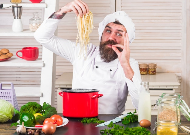 Chef barbuto con spaghetti. Tagliatelle. Cuoco maschio in uniforme con segno perfetto.