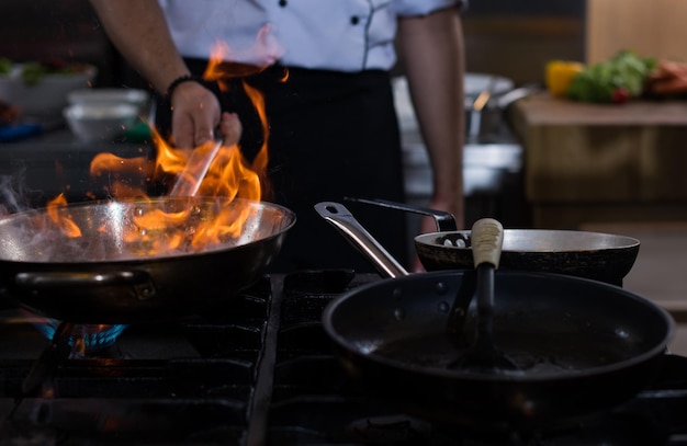 Chef che cucina e fa flambe sul cibo nella cucina del ristorante