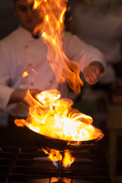 Chef che cucina e fa flambe sul cibo nella cucina del ristorante