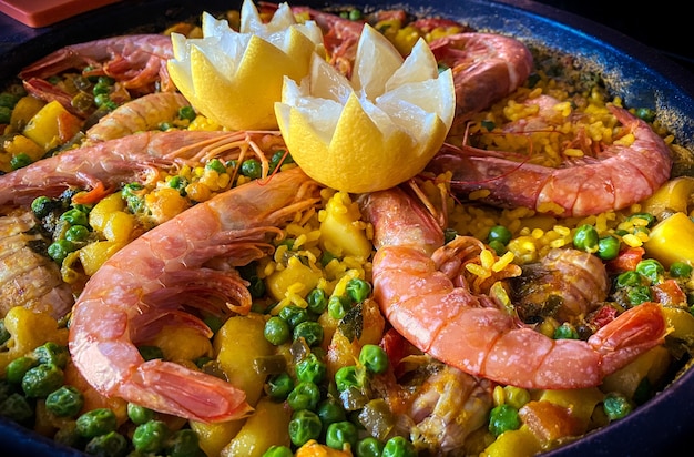 Chef che cucina una paella spumeggiante con gamberi, limone e frutti di mare assortiti. Preparare la tipica tapa spagnola deliziosa. Gustoso piatto di Spagna