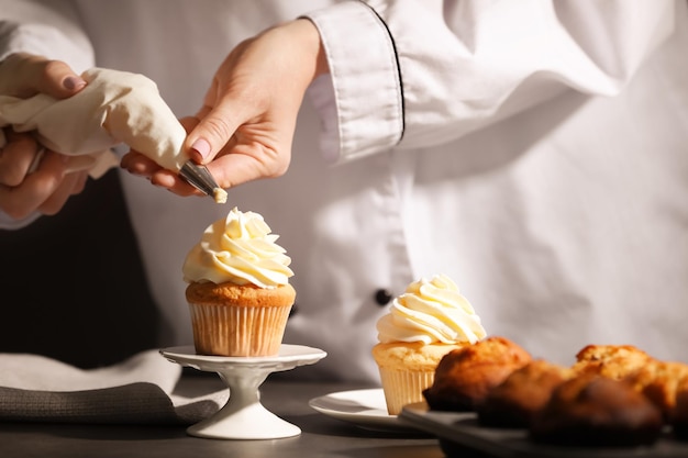 Chef che decora una gustosa cupcake con crema a tavola