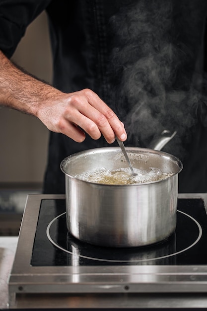 Chef che fa bollire l'acqua in una pentola d'acciaio