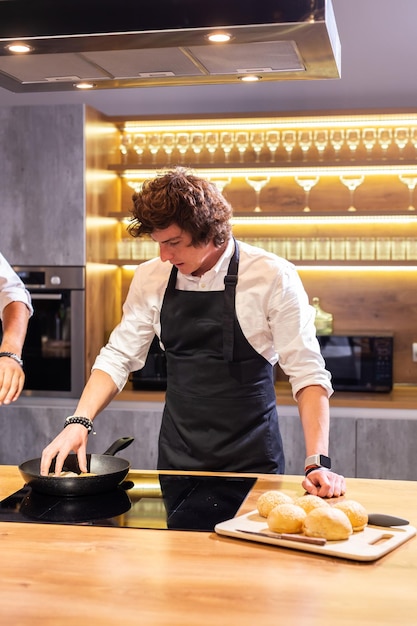 Chef che frigge panini per hamburger per la cena in cucina