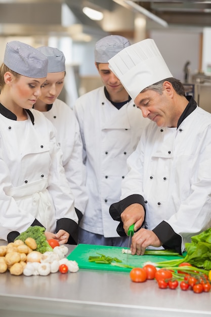 Chef che insegna il taglio di verdure a tre tirocinanti