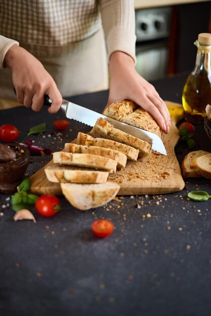 Chef che taglia il pane fresco su una tavola da taglio in legno sul tavolo della cucina