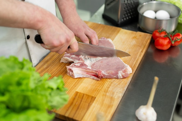 Chef che taglia la carne su una tavola di legno