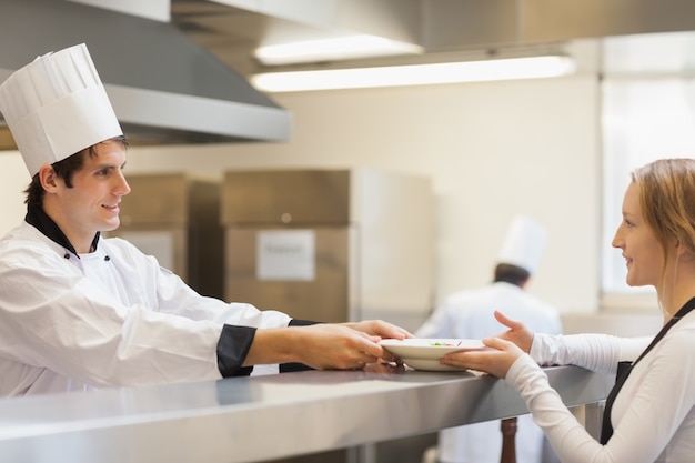 Chef dando un piatto alla cameriera