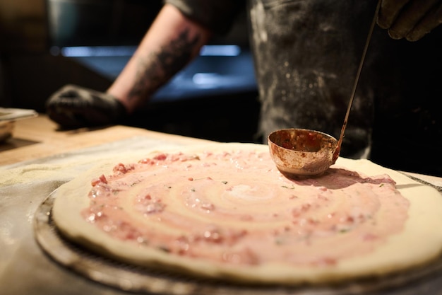 Chef del ristorante che spalma miscela di ingredienti su focaccia