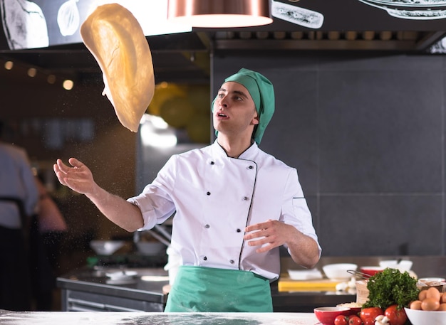 Chef esperto che prepara l'impasto per la pizza arrotolando con le mani e vomitando