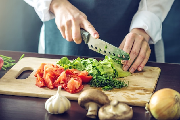 Chef in grembiule nero tagliare le verdure