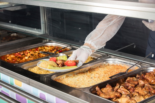 Chef in piedi dietro la stazione di servizio per il pranzo completo