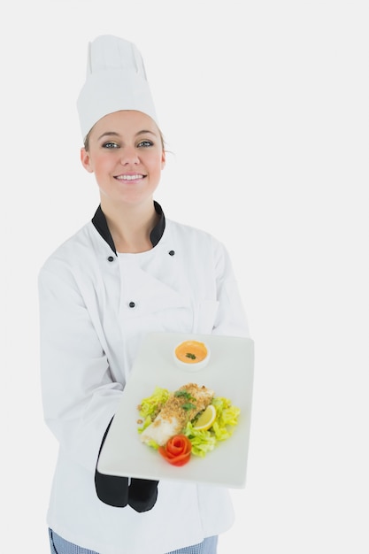 Chef in uniforme che offre un piatto di cibo sano