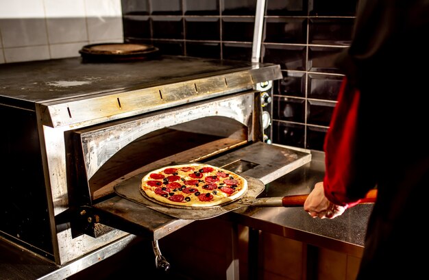 Chef mettendo la pizza in forno per cucinare