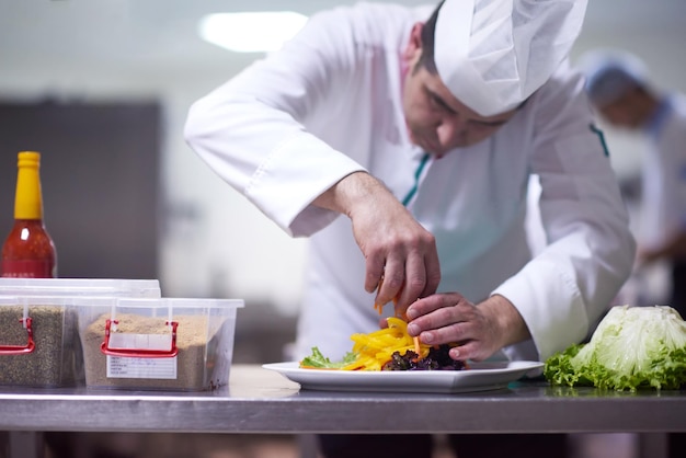 chef nella cucina dell'hotel che prepara e decora il cibo, deliziose verdure e cena a base di carne