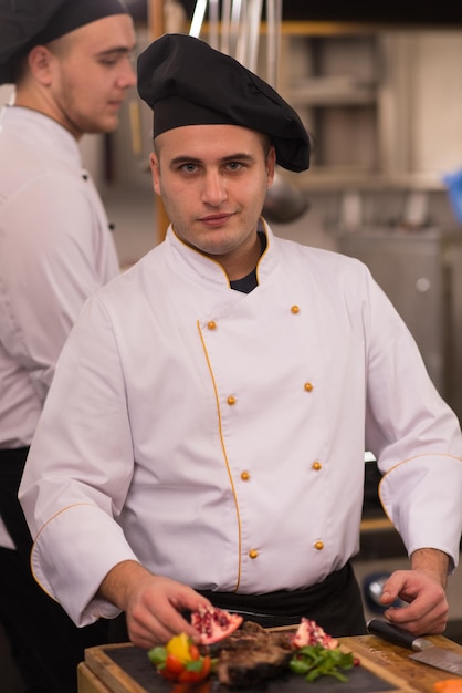 Chef nella cucina dell'hotel o del ristorante che prepara bistecca di manzo con decorazione vegetale