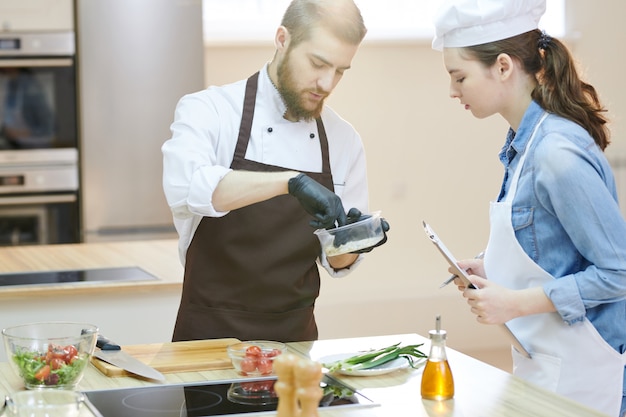 Chef professionista che lavora in cucina con assistente femminile