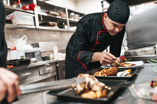 Chef professionista che organizza il piatto di cibo con carne e verdure