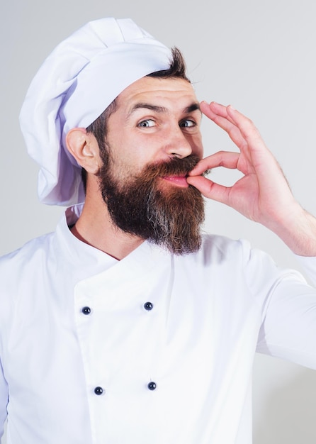 Chef professionista in uniforme bianca che mostra il perfetto segno di cucina professionale e concetto di cibo