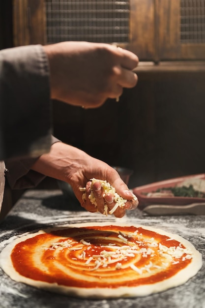 Chef spalmabile a mano concentrato di pomodoro su base pizza, preparando un pasto italiano tradizionale con salsa marinara, copia spazio