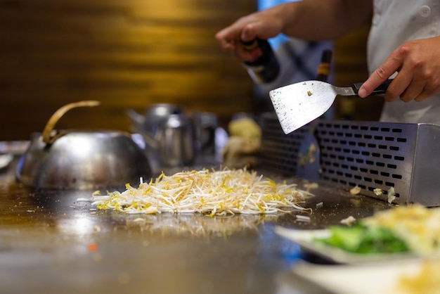 Chef Teppanyaki che prepara il cibo su una piastra di metallo caldo