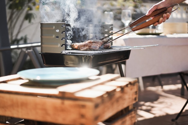 Chef uomo che cucina carne al barbecue cena a casa all'aperto nel giardino sul retro