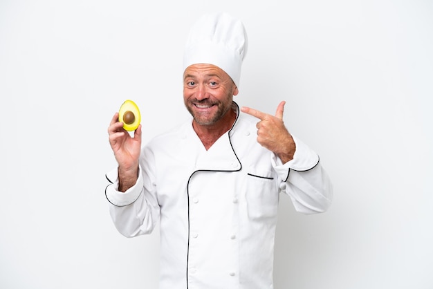 Chef uomo che tiene un avocado isolato su sfondo bianco dando un pollice in alto gesto