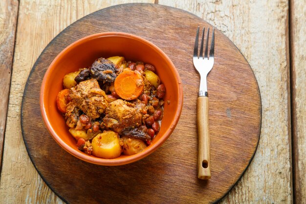 Chelnt piatto ebraico con carne sul tavolo in un piatto su un supporto rotondo.