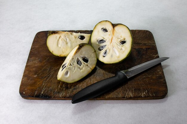 cherimoya frutta esotica peruviana il frutto viene tagliato in tre fette apprezzando il suo cibo e i semi si siede su una tavola di legno marrone accanto a un coltello da cucina