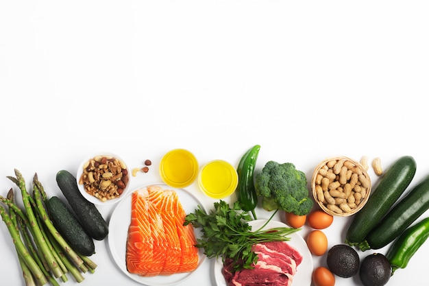 Chetogeno, dieta cheto, comprese verdure, carne e pesce, noci e olio su sfondo bianco con spazio di copia