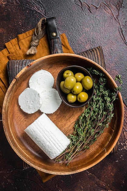 Chevre di formaggio di capra morbido in un piatto con timo e olive Sfondo scuro Vista dall'alto