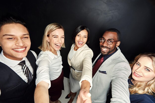 Chi ha detto che non potevamo fare selfie al lavoro Ritratto di un gruppo di uomini d'affari che scattano un selfie su uno sfondo scuro