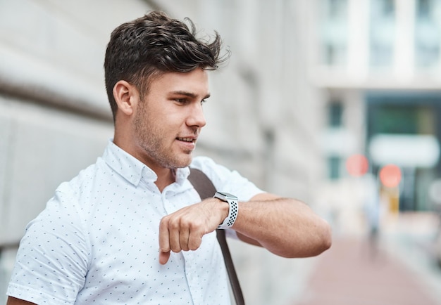 Chiacchierando su uno smartwatch con un giovane uomo d'affari creativo o uno stagista che si sposta in città Chiamando un taxi o un giro con un'app su tecnologia wireless Dipendente di sesso maschile che viaggia da e per il lavoro