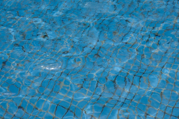 chiara superficie dell'acqua in piscina con piastrelle blu. design della piscina tropicale. ondeggia lentamente.