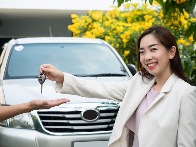 Chiave asiatica dell'automobile della tenuta della donna ad un uomo. guida di veicoli, viaggio, noleggio di veicoli, assicurazione di sicurezza