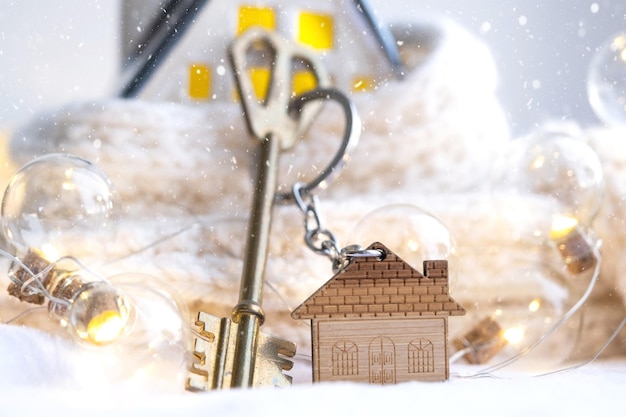 Chiave della casa con un portachiavi in una casa accogliente con decorazioni natalizie Un regalo per Capodanno Natale Progetto di progettazione edilizia trasferirsi in una nuova casa affitto ipotecario e acquisto di immobili