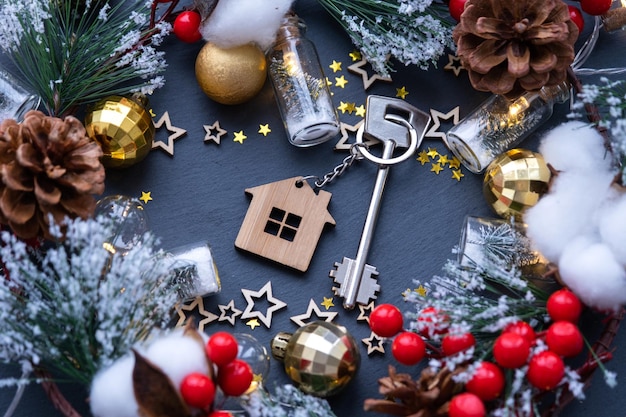 Chiave della casa con un portachiavi su sfondo nero con layout di decorazioni natalizie Un regalo per Capodanno Natale Progetto di progettazione di edifici che si trasferiscono in una nuova casa mutuo affitto e acquisto di immobili