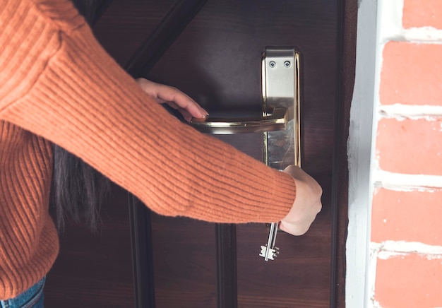 Chiave della mano della donna sulla porta di casa