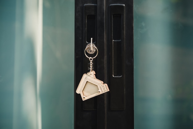 Chiave di casa su un portachiavi d'argento a forma di casa nella serratura di una porta d'ingresso