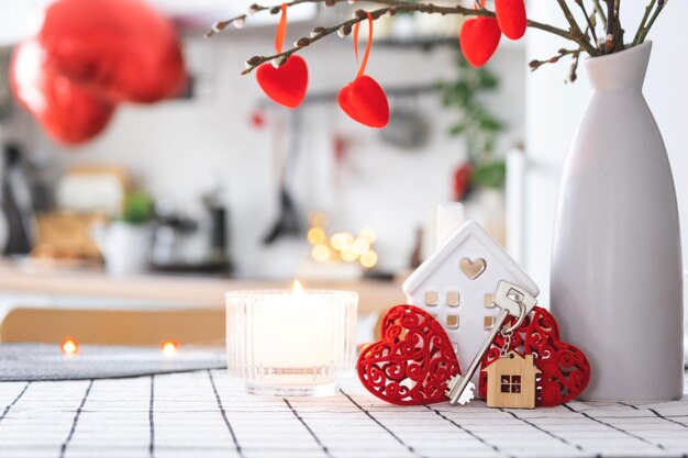 Chiave per la casa di una casa accogliente con decorazioni di San Valentino sul tavolo della cucina Regalo per il nido d'amore della famiglia di San Valentino Progetto di progettazione dell'edificio trasloco in una nuova casa affitto ipotecario e acquisto di immobili