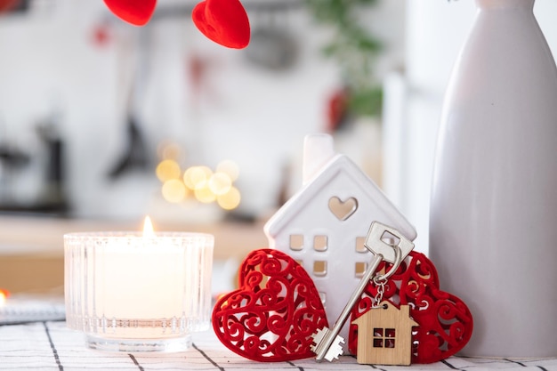 Chiave per la casa di una casa accogliente con decorazioni di San Valentino sul tavolo della cucina Regalo per il nido d'amore della famiglia di San Valentino Progetto di progettazione dell'edificio trasloco in una nuova casa affitto ipotecario e acquisto di immobili