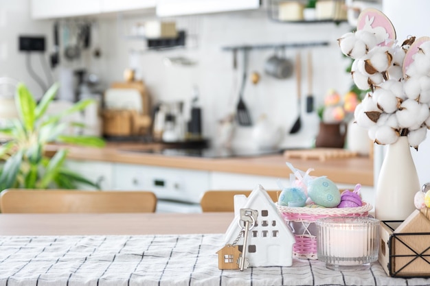 Chiave per la casa di una casa accogliente con decorazioni pasquali con coniglio e uova sul tavolo della cucina Progetto di progettazione edilizia trasferirsi in una nuova casa mutuo assicurazione affitto e acquisto di immobili