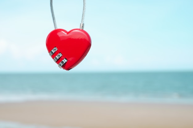 Chiave rossa di forma del cuore con la spiaggia ed il mare di estate Il concetto del biglietto di S. Valentino.