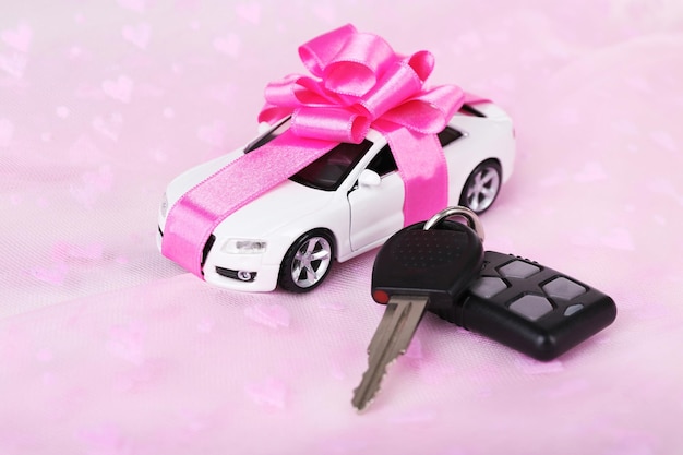 Chiavi e auto con fiocco presenti su sfondo rosa