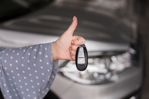 Chiavi femminili dell'automobile della tenuta della mano e mostrare segno giusto