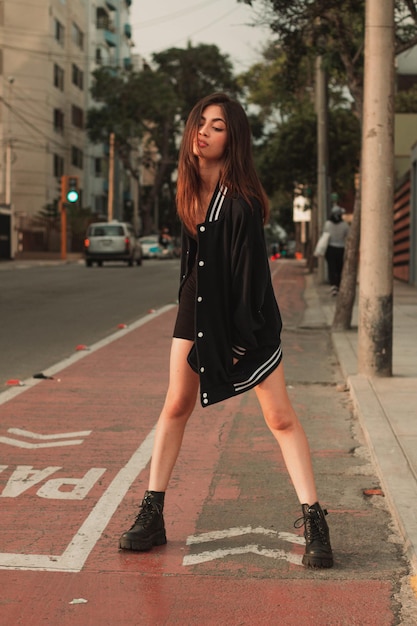 Chica joven vestida de negro en medio de una ciclovia bailando