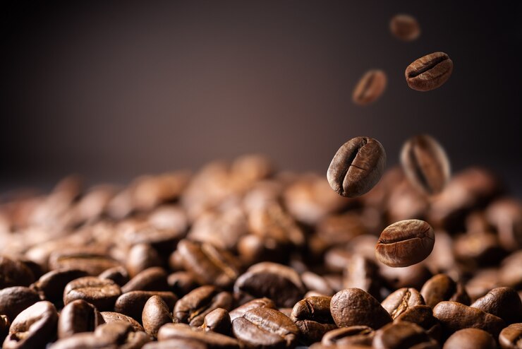 Chicchi di caffè al fabrique. I chicchi di caffè cadono sul tavolo. Sfondo fatto di chicchi di caffè freschi che cadono con spazio di copia