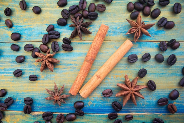 Chicchi di caffè, bastoncini di cannella e anice stellato su fondo in legno dipinto in blu e oro. avvicinamento.