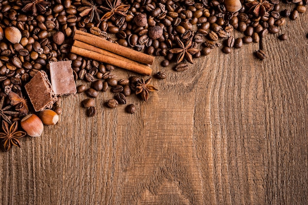 Chicchi di caffè cannella anice stellato nocciole al cioccolato su un tavolo di legno